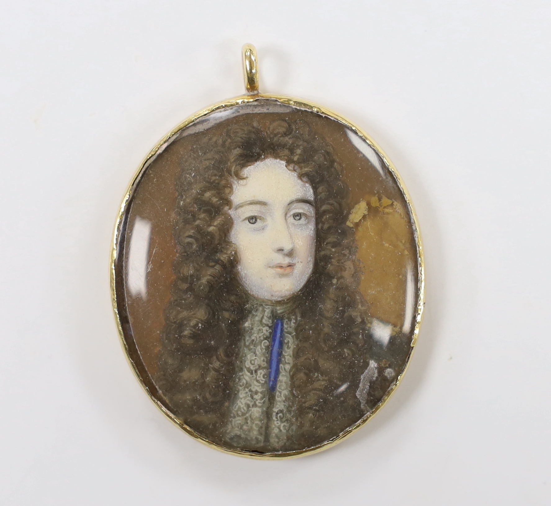 A 19th century yellow metal mounted oval pendant with inset watercolour on ivory miniature portrait bust of a gentleman, verso with engraved monogram with motto and coronet, overall, 55mm, gross weight 24.9 grams (a.f.).